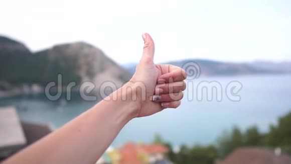 女性在阳台上缓慢动作的海洋背景上的OK手势视频的预览图