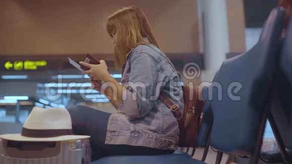 慢动作快乐的亚洲女人在候机大厅坐在椅子上在起飞时等待她的航班视频的预览图