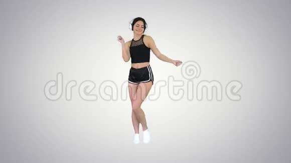 年轻快乐的运动女性在耳机里听音乐在梯度背景下跳舞视频的预览图