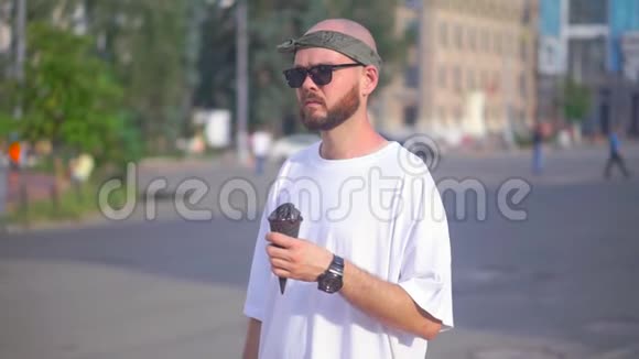 戴着太阳镜和一件白色T恤的年轻人站在街上手里拿着一个冰淇淋筒视频的预览图