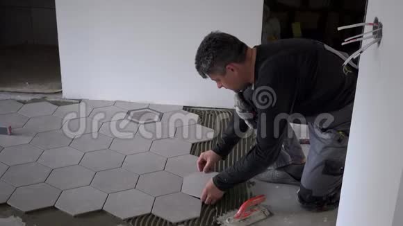 仔细观察建筑工人在水泥地面上铺设六角砖视频的预览图