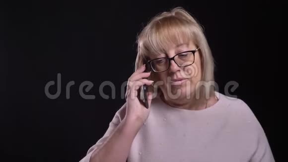 戴眼镜的白种人老金发奶奶用背景镜头前打电话的特写镜头视频的预览图