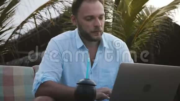 近距离严肃专注的高加索商人使用笔记本电脑在移动办公室和平棕榈树下工作视频的预览图