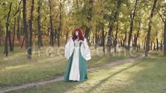 漂亮可爱的女士一头红色的卷发一身绿色宽松的民族服装的丰满的大模特手里拿着苹果视频的预览图
