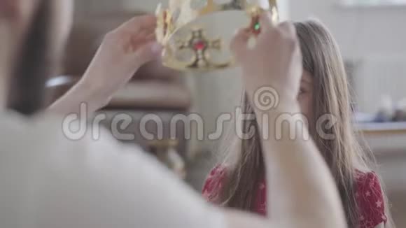 年轻的父亲把皇冠放在他的小女儿的头上让她的公主靠近女孩很开心她视频的预览图