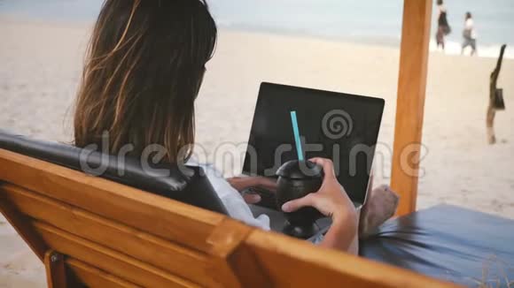 后景成功女商人与饮料工作笔记本电脑金融图表在躺椅上惊人的海洋海滩视频的预览图