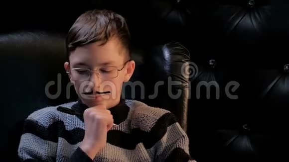 一个穿条纹毛衣的年轻人坐在一张黑色扶手椅上一个留着粘着胡子的少年手里拿着一支笔视频的预览图
