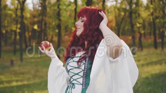美丽的仙女公主看着手中的神奇苹果丰满的大模型红色的长发绿色的爱尔兰视频的预览图