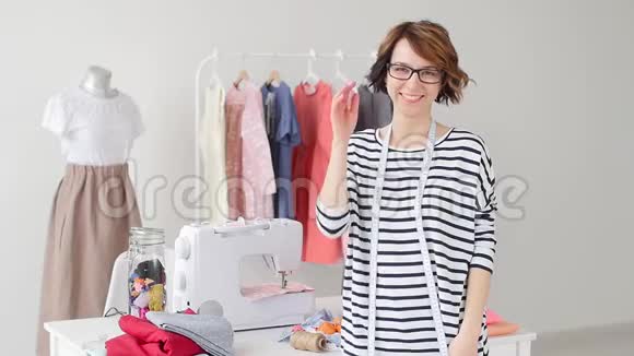 小企业和爱好概念年轻女裁缝在他的工作室里对着他们的产品微笑视频的预览图