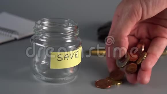 手把硬币放在储蓄的玻璃罐旁边上面刻着萨维视频的预览图