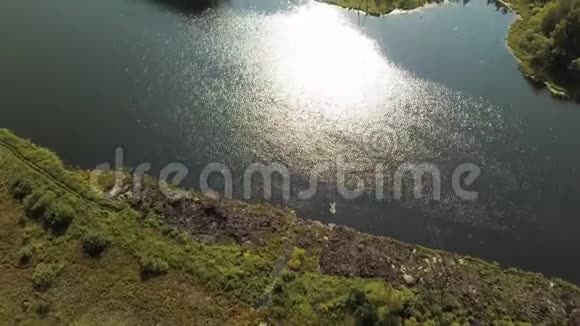 空中夏季景观的绿谷小村庄和湖面上的阳光反射股票视频的预览图