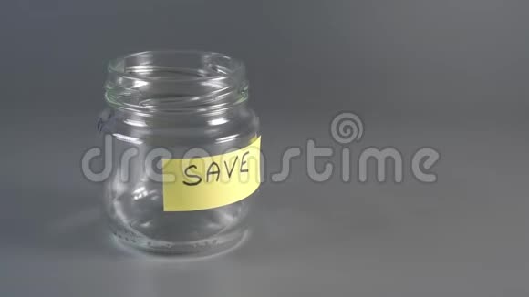 手把硬币放在储蓄的玻璃罐旁边上面刻着萨维视频的预览图