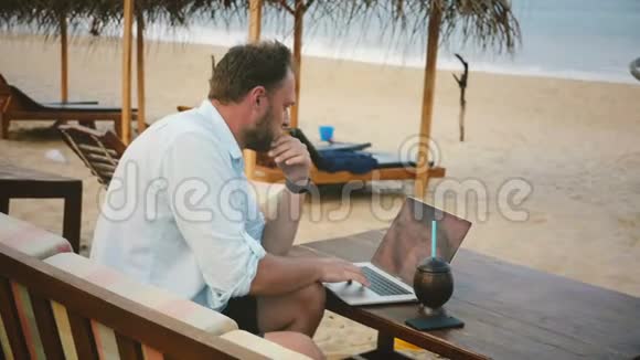 后视中镜头成功轻松商人使用笔记本电脑在线异国情调的夏季海滨度假海滩视频的预览图