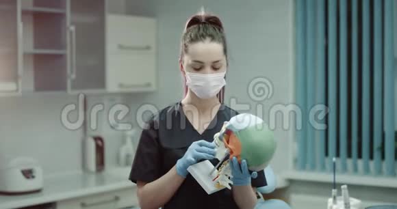 年轻的护士助理在镜头前在一个现代诊所的房间里手里拿着一个巨大的医学头骨视频的预览图