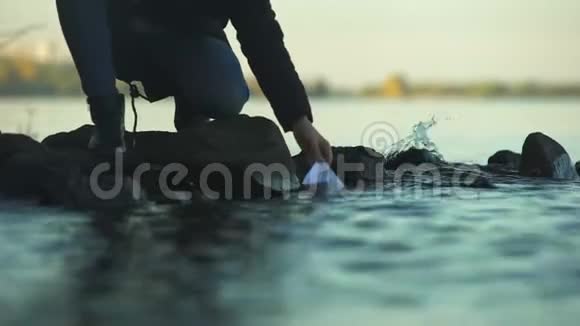 男人把纸船放在水上告别过去心理治疗特写视频的预览图
