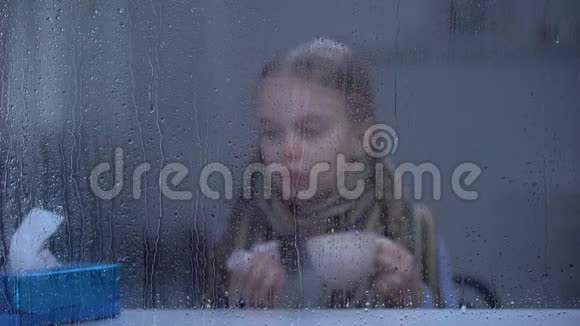 生病的女孩打喷嚏在雨窗后喝热茶流感病毒流行视频的预览图