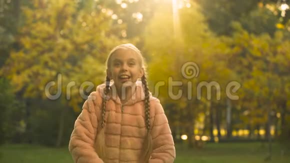 开朗的女孩扔秋叶享受秋天的季节玩得开心快乐视频的预览图