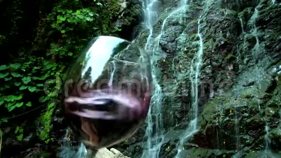 红酒在背景岩石和瀑布中溅入杯中视频的预览图