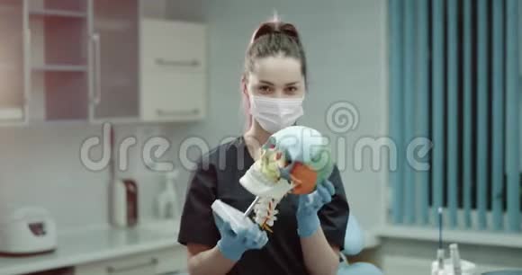 年轻的医生助理戴着外科口罩和手套在一个现代化的诊所里在镜头前检查一个视频的预览图