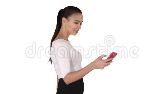 年轻的女人带着购物袋走路在白色的背景上用手机说话视频的预览图
