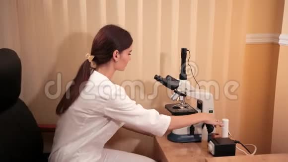 医学年轻的女医生穿医用长袍的护士使用显微镜视频的预览图