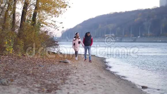 情人男女走在河边的秋天笑着互相握住对方手视频的预览图