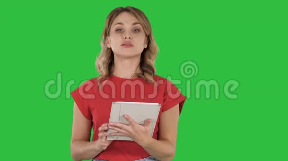 穿着红色T恤的女士手里拿着一块平板电脑严肃的脸对着绿色屏幕上的摄像机说话Chroma视频的预览图
