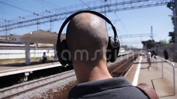 魅力十足的光头男一边坐火车一边听着耳机里的音乐视频的预览图