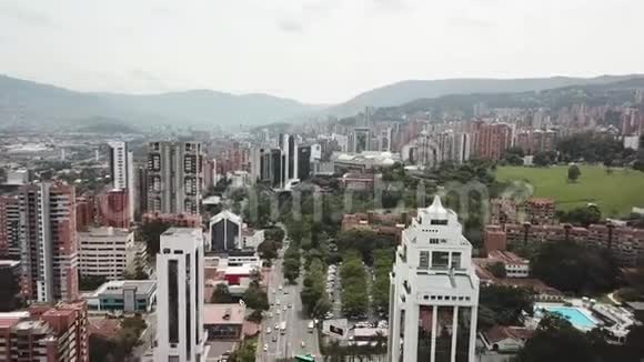 向后飞行的无人机鸟瞰哥伦比亚麦德林市显示交通和被群山包围的建筑物视频的预览图