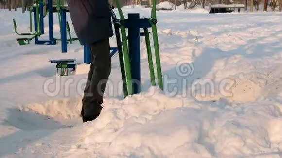 特写男的腿正在城市的一个冬季公园里用模拟器做运动后景视频的预览图