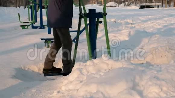 特写男的腿正在城市的一个冬季公园里用模拟器做运动侧视视频的预览图