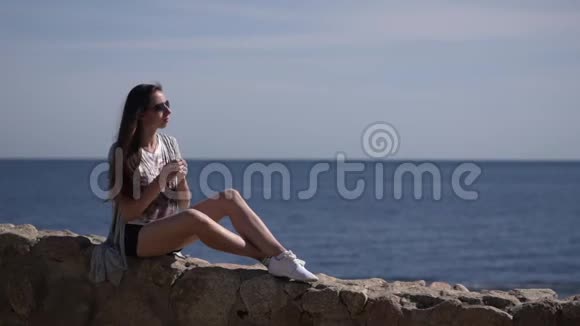 女孩坐在石头上玩她的头发视频的预览图