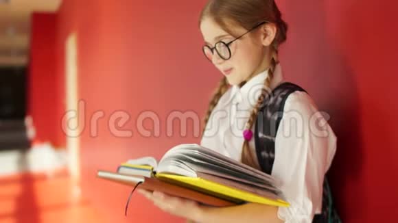 一个戴眼镜的可爱女孩的肖像女学生手里拿着书背着一个书包背到视频的预览图