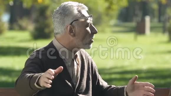 老年男性在公园给朋友讲故事新闻讨论养老金领取者谈话视频的预览图