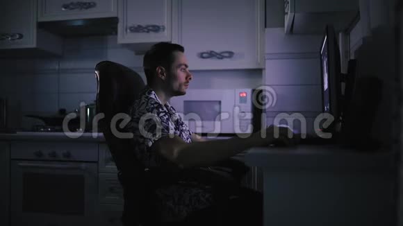 他在黑暗的厨房里做视频剪辑工作蓝光屏视频的预览图