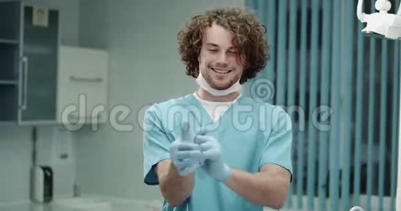 年轻有魅力的牙医或外科医生在镜头前非常高兴和微笑的医院房间把他的视频的预览图
