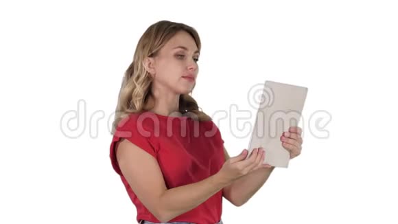 金发少女手里拿着平板电脑打个视频电话或录制视频在白色背景上微笑视频的预览图