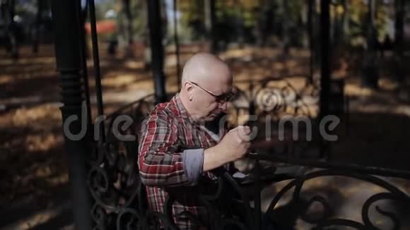 一位老人在秋天公园的凉亭里读一本电子书视频的预览图