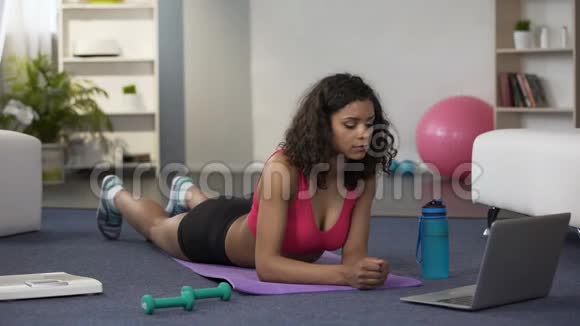 混合种族的年轻女性在笔记本电脑前做在线锻炼锻炼身体视频的预览图