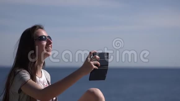海滩上的女孩打视频电话打招呼视频的预览图