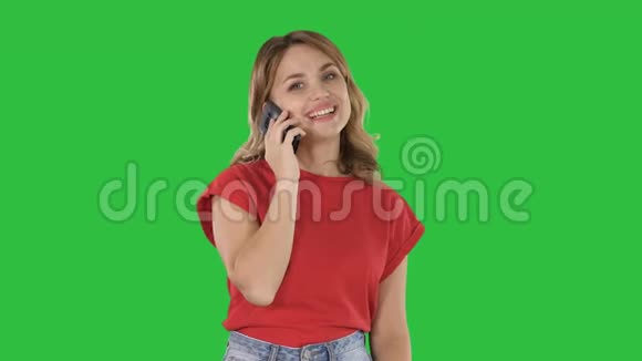 年轻的漂亮女人穿着红色t恤在绿色屏幕上的手机上说话Chroma键视频的预览图