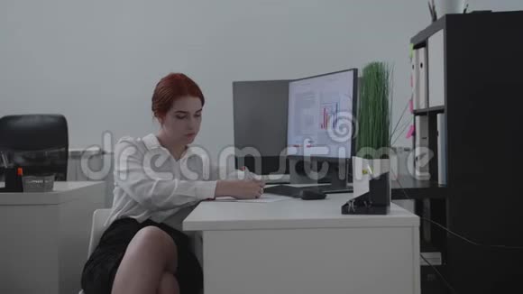 年轻女子坐在办公室的一张桌子旁视频的预览图