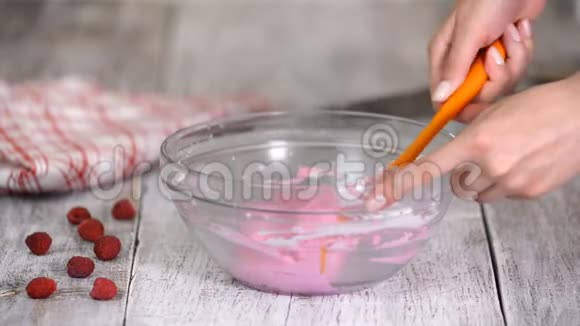 手搅拌香草奶油与粉红色在混合碗视频的预览图