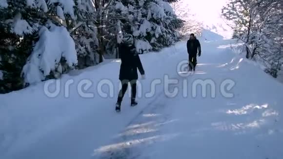 年轻的幸福家庭在雪林里玩得很开心父母把他们的小儿子卷在雪橇上父母亲吻慢慢视频的预览图