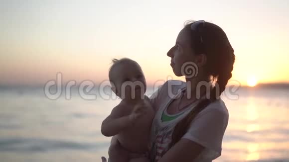 可爱的家庭乐趣母亲和婴儿在日落时摇动他们的手视频的预览图