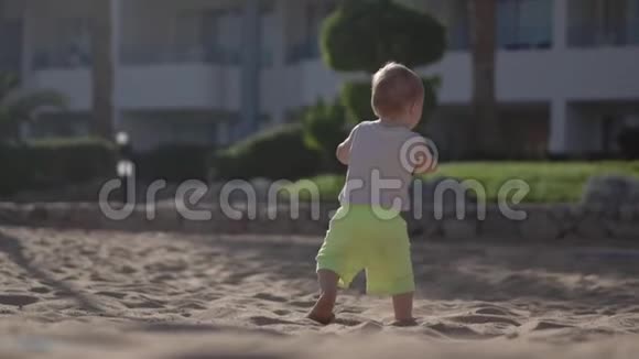 小宝宝在海滩上慢动作地用手拿着球走路视频的预览图