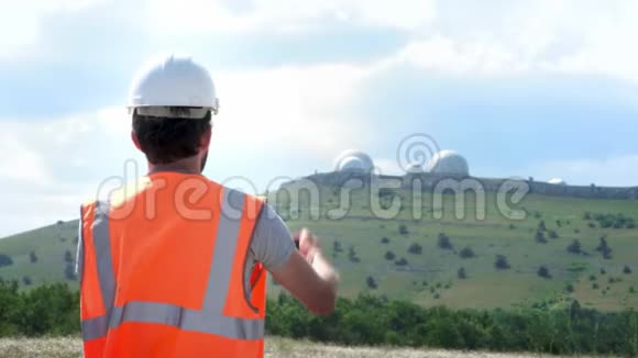 一位身穿白色头盔和背心的男工程师或建筑工人拍摄了山顶天文台的照片视频的预览图