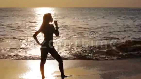 日落时海滩上神秘的剪影女孩视频的预览图