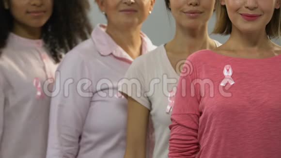 一群健康的女人带着粉红色的丝带对着镜头微笑抗癌运动视频的预览图