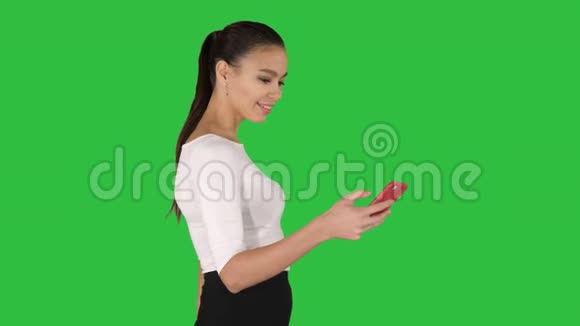 年轻女子带着购物袋在绿色屏幕上的手机上交谈Chroma键视频的预览图